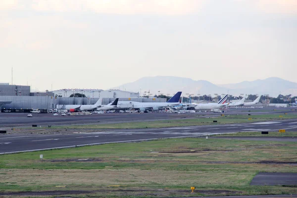 Ticari uçak park etmiş, kalkıyor ya da mavi gökyüzünün altında büyük bulutlarla iniş yapıyor.