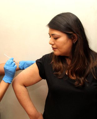 40 yaşında mutlu ve korkmuş bir kadın kolunda kovid 19 aşısı olmasından korkuyor.