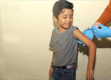 7 yaşındaki Latin çocuk koluna aşı aşısı vuruluyor. Mutlu ve korkmuş.