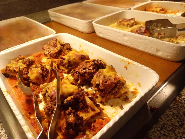 Büfede hazırlanmış lezzetli yemekler: lazanya, kek, peynir, ceviche ve maşalı patates.