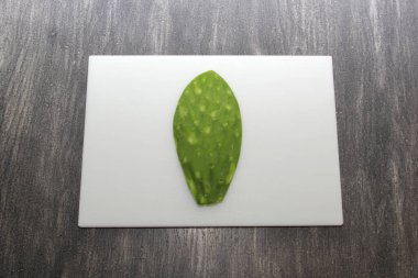 Taze yeşil Meksikalı göçebeler, gri ahşap bir masanın üzerinde beyaz bir kesim tahtasının üzerinde pişirmeye hazırlar.