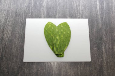 Taze yeşil Meksikalı göçebeler, gri ahşap bir masanın üzerinde beyaz bir kesim tahtasının üzerinde pişirmeye hazırlar.