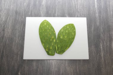 Taze yeşil Meksikalı göçebeler, gri ahşap bir masanın üzerinde beyaz bir kesim tahtasının üzerinde pişirmeye hazırlar.