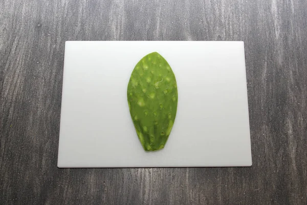 Taze yeşil Meksikalı göçebeler, gri ahşap bir masanın üzerinde beyaz bir kesim tahtasının üzerinde pişirmeye hazırlar.