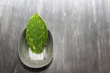 Çiğ omurgasız yeşil nopallar, Meksika yemeği için vazgeçilmez ahşap bir masada örülmüş sepetle pişirmeye hazırlar.