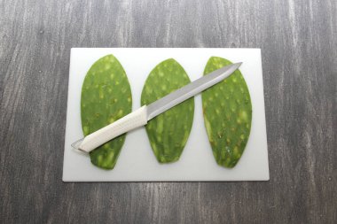 Çiğ, taze, yeşil Meksikalı nopallar doğrama tahtasında ve bıçakla pişirmeye hazır.