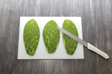 Çiğ, taze, yeşil Meksikalı nopallar doğrama tahtasında ve bıçakla pişirmeye hazır.