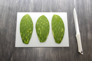 Çiğ, taze, yeşil Meksikalı nopallar doğrama tahtasında ve bıçakla pişirmeye hazır.