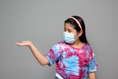 Kendini koronavirüsten korumak için maske takan mutlu küçük bir Latin kız. Yeni normal hastalık yüzünden.