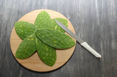 Kemikleri olmayan taze, çiğ yeşil nopallar. Bıçaklı bir tahta üzerinde Meksika yemeği pişirmeye hazırlar.