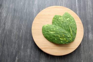 Kemikleri olmayan taze, çiğ yeşil nopallar. Bıçaklı bir tahta üzerinde Meksika yemeği pişirmeye hazırlar.