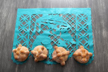 Tahta masadaki Papel Picado masa örtüsü Meksika Ölüler Günü süslemesi gibi Lezzetli, pofuduk ve şekerli ölü ekmeğiyle
