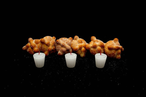 Пушистый, вкусный и свежий мексиканский хлеб из мертвых со свечами в качестве подношения ко Дню верующих умерших и всех святых на траурном черном фоне