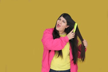 30 yaşındaki Latin kadın, uzun düz saçlarını tarıyor. Hasarlı, susuz ve karışık saçlardan muzdarip.