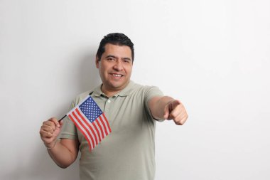 Esmer tenli Latin yetişkin adam, göçmen olarak yeni uyruğu olan ABD bayrağını sergiliyor.
