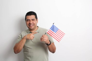 Esmer tenli Latin yetişkin adam, göçmen olarak yeni uyruğu olan ABD bayrağını sergiliyor.