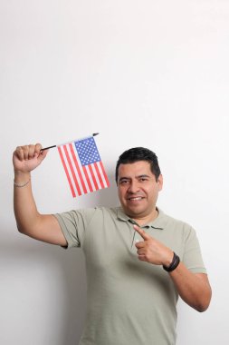Esmer tenli Latin yetişkin adam, göçmen olarak yeni uyruğu olan ABD bayrağını sergiliyor.