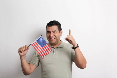 Esmer tenli Latin yetişkin adam, göçmen olarak yeni uyruğu olan ABD bayrağını sergiliyor.