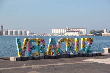 Veracruz, Meksika - 26 Ekim 2025: Veracruz ticari limanın arka planında deniz, kargo gemisi ve San Juan de Ulua Kalesi 'nin iskele levhası