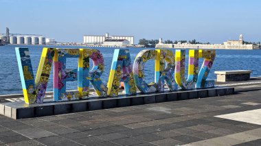 Veracruz, Meksika - 26 Ekim 2025: Veracruz ticari limanın arka planında deniz, kargo gemisi ve San Juan de Ulua Kalesi 'nin iskele levhası