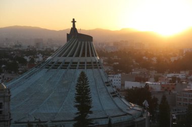 Mexico City, Mexico - 25 Kasım 2024: Günbatımı CDMX 'te Guadalupe Bazilikası' na tepeden bakan bakış açısını aydınlatıyor.