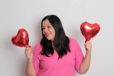 40 yaşındaki Latin kadın sevgililer gününü kutluyor ve aşkını kalp şeklinde balonlarla gösteriyor çünkü aşık.