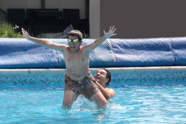 Bekar baba, 11 yaşındaki Latin oğluna havuzda yüzmeyi öğretiyor.