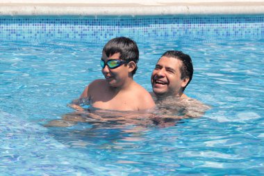 Bekar baba, 11 yaşındaki Latin oğluna havuzda yüzmeyi öğretiyor.