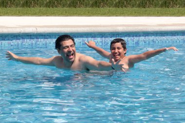 Bekar baba, 11 yaşındaki Latin oğluna havuzda yüzmeyi öğretiyor.