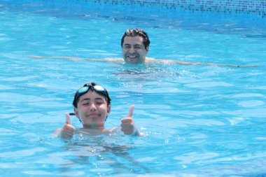 Bekar baba, 11 yaşındaki Latin oğluna havuzda yüzmeyi öğretiyor.