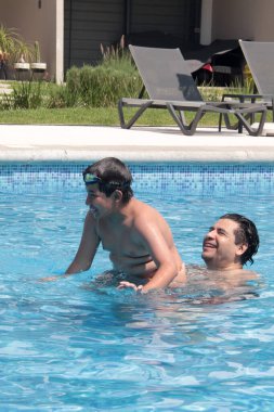Bekar baba, 11 yaşındaki Latin oğluna havuzda yüzmeyi öğretiyor.