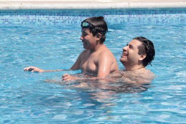 Bekar baba, 11 yaşındaki Latin oğluna havuzda yüzmeyi öğretiyor.