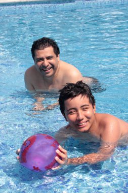 Bekar baba, 11 yaşındaki Latin oğluna havuzda yüzmeyi öğretiyor.