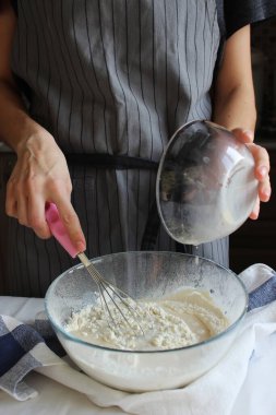 Ev hanımı. Bir ev kadınının elleri hamuru yoğurmak için bir kase una malzemeleri ekler. Aile kutlaması. Kapat..