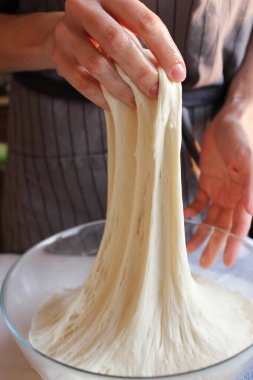 Ev hanımı. Kadın bir ev kadınının elleri hamuru büyük bir kasede yoğurur. Aile kutlaması. Kapat..