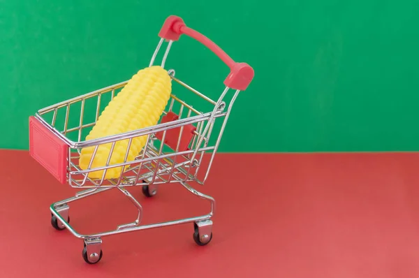 Carrito Compras Sobre Fondo Rojo Verde Con Maíz Plástico Interior — Foto de Stock