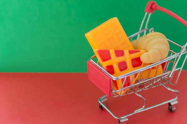 Kırmızı Yeşil Arka Planda Alışveriş Sepeti Içinde Plastik Pizza Kruvasan — Stok fotoğraf