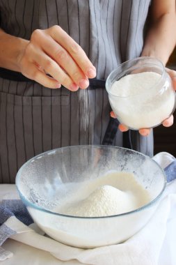 Ev hanımı. Bir ev kadınının elleri hamuru yoğurmak için bir kase una malzemeleri ekler. Aile kutlaması. Kapat..