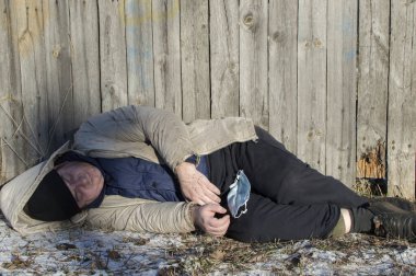 Salgın. Tıbbi maskeli bir adam ellerini parmaklıkların üzerinde tutuyor. Kapat..