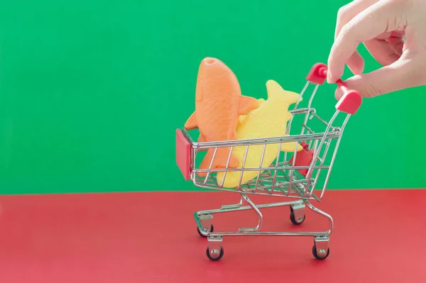 Una Mano Sostiene Carrito Compras Sobre Fondo Rojo Verde Con — Foto de Stock