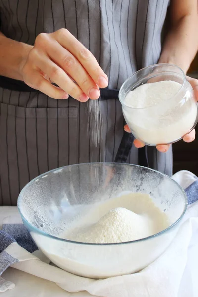 Ev hanımı. Bir ev kadınının elleri hamuru yoğurmak için bir kase una malzemeleri ekler. Aile kutlaması. Kapat..