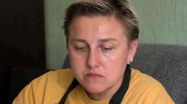 Sarı elbiseli bir kız, çok iştah açıcı yiyor, alnında bir sivilceyle yemek çiğniyor.