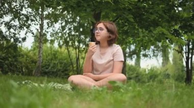A teenage girl enjoys a delicious ice cream cone in the summer. A child with ice cream on a walk in a city park
