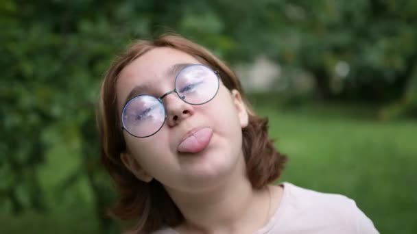 公園のカメラには眼鏡をかけた10代の少女が面白い顔をしている 愚かさと楽しさ — ストック動画