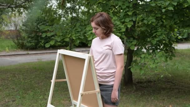 一个红头发的少女用画笔在画架上画画 画中的自然 发展儿童创造力的概念 — 图库视频影像