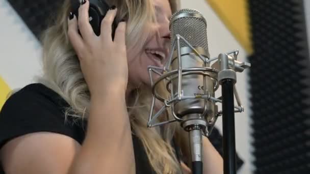 Ein Blondes Mädchen Mit Kopfhörern Singt Einem Tonstudio Mikrofon Ein — Stockvideo