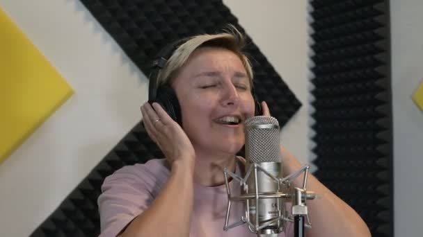 Ein Blondes Mädchen Mit Kopfhörern Singt Einem Tonstudio Mikrofon Ein — Stockvideo