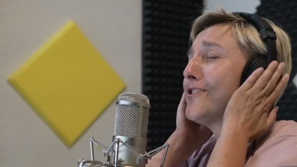 Ein Blondes Mädchen Mit Kopfhörern Singt Einem Tonstudio Mikrofon Ein — Stockvideo