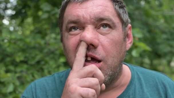 A mentally retarded, toothless, unshaven man picks his nose and drools. The  concept of mental illness. 4k video format. 498246850