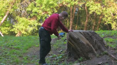 Kulaklık takan ve kırmızı tişörtlü bir adam sabit bir dengeleyici kullanarak telefonuyla video çekiyor.